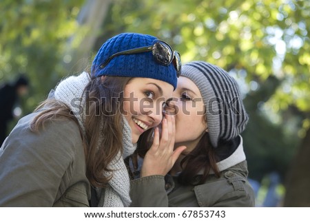 The woman whispers in ear to other woman