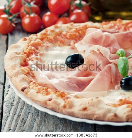 Italian traditional pizza with mozzarella, ham and basil, selective focus