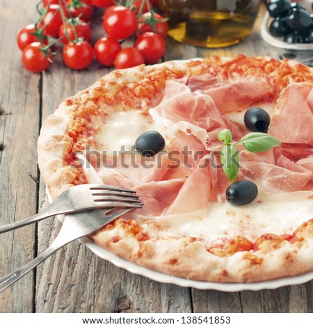 Itaditional pizza with mozzarella, ham and basil, selective focus and square image