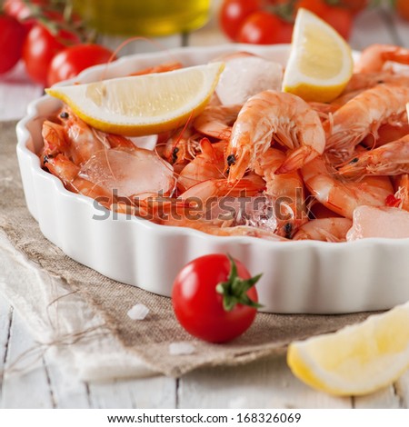 Raw fresh shrimp with lemon, tomato and ice, selective focus and square image