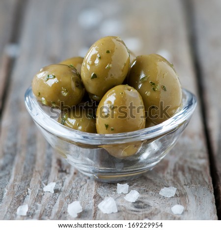 Green italian olives on the wooden table, selective focus and square image