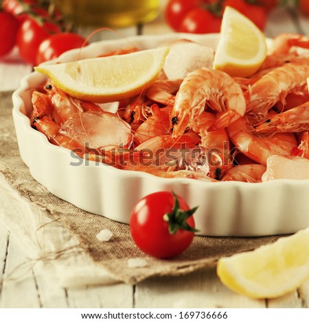 Raw fresh shrimp with lemon, tomato and ice, selective focus and square image, retro style