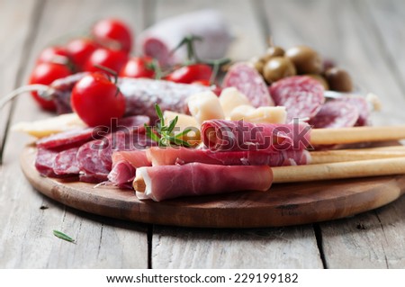 Traditional italian antipasto with prosciutto, cheese, olive and sausage, selective focus