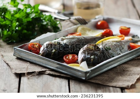 Cooked fish with parsley, tomato and lemon, selective focus