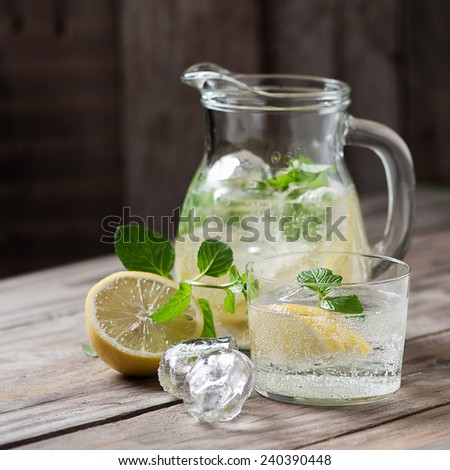 Lemonade with fresh lemon and mint on wooden background, square image