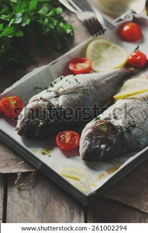 Cooked fish with parsley, tomato and lemon, selective focus and toned image