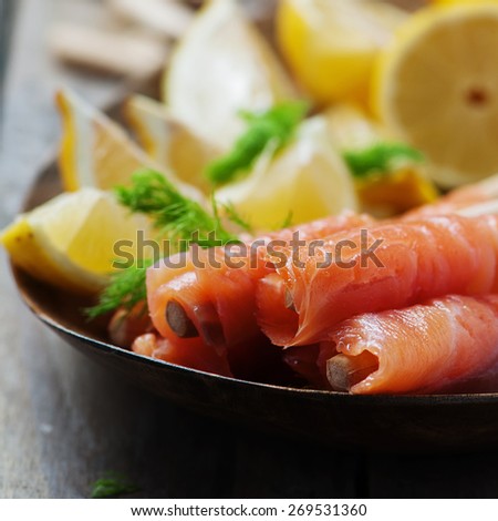 Smoked salmon with grissini and lemon, selective focus and square image