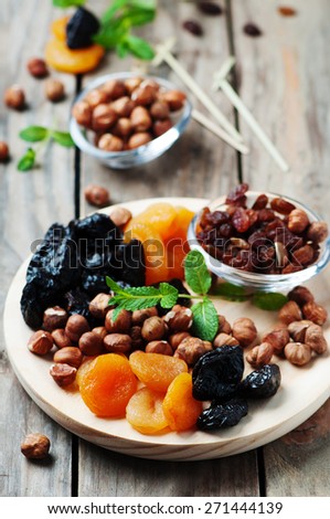 Concept of vegan dessert with dry apricots, plums, raisins and nuts, selective focus