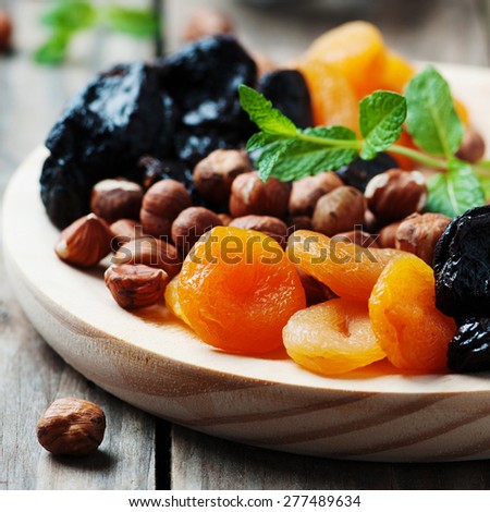 Concept of vegan dessert with dry apricots, plums, raisins and nuts, selective focus and square image