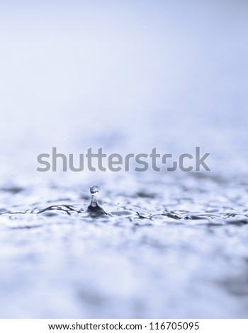 Raindrop falling on a lake surface. You can see the reflection of the lake in the drop.