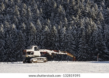 A snow-covered  abandoned excavator.