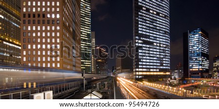 Panoramic long time  exposure of trains passing by skyscrapers in central Tokyo at night.