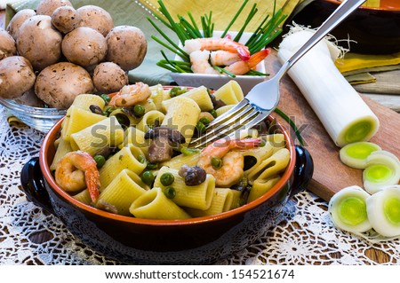 Shrimp and Mushroom Pasta in ceramic clay pot with a fork and accessories on wooden table