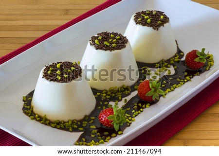 Vanilla italian dessert with chocolate and strawberries on wooden table