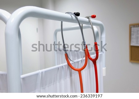 a pair of stethoscopes hung on hospital cover in hospital room