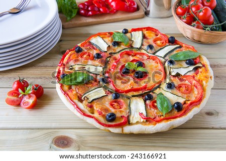 italian pizza with black olives, cherry tomatoes, eggplants and peppers on woodenboard
