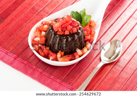 Chocolate pudding with strawberries in white plat on wooden table