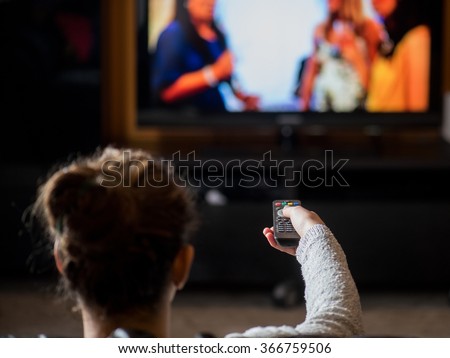 young girl watching TV with remote control in living home