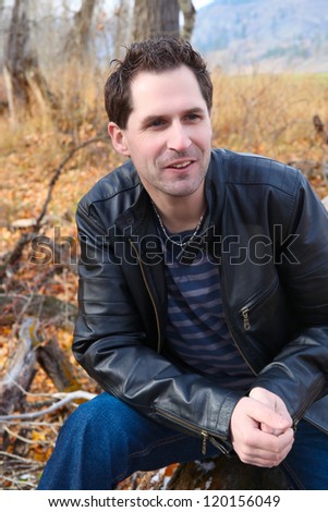 Attractive male model in the field wearing a leather jacket