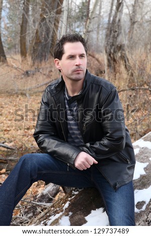 Brunette male model outdoors wearing leather jacket and jeans