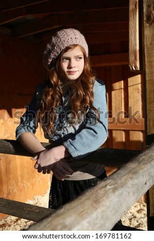 Red haired winter girl standing in barn