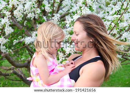 Little blond girld and her mom in a spring blossom garden