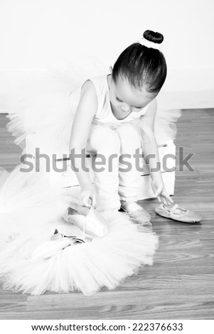 Little ballet girl trying on shoes at the ballet studio