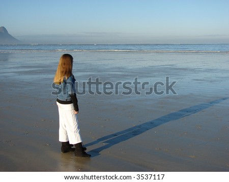 Young girl standing on the beach, looking into the far distance Young girl standing on the beach, looking out to see Head & Shoulders shot of a young girl on the beach, with pearls around her neck