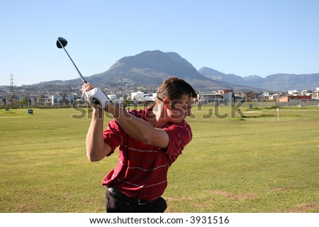 Young golfer on the driving range taking a back swing Follow Through of a young professional golfer whilst practising on the range