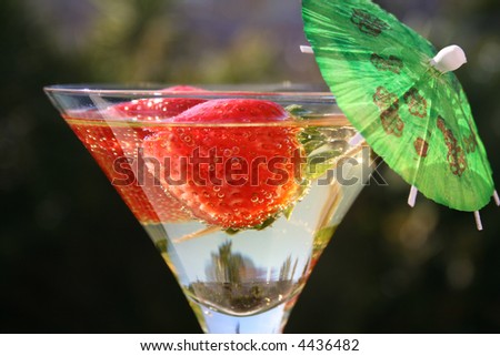 Strawberries in a martini glass with an umbrella in the sun