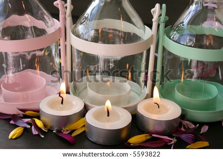 Three candle-holders with lit candles in front of them