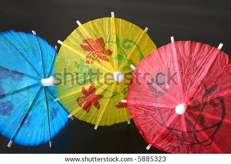 Blue, yellow and red Cocktail Umbrellas on a dark surface