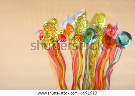Different colored cocktail sticks with shapes on a soft gold background