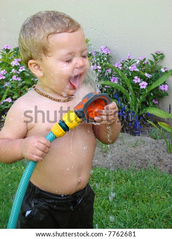Toddler playing outside in the garden with the sprinklers