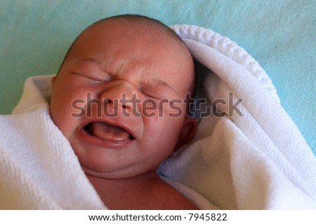 Week old baby boy wrapped in a blanket, crying early in the morning