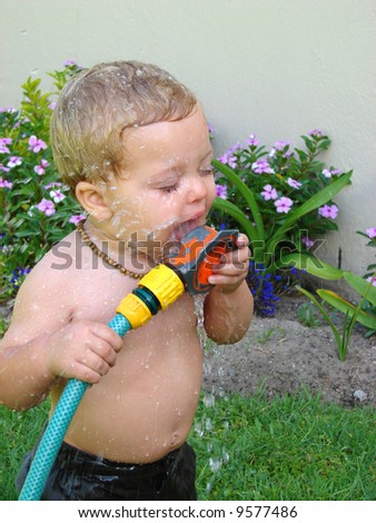 Toddler playing outside in the garden with the sprinklers