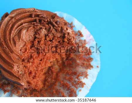 Chocolate cupcake decorated with icing which has a bite missing