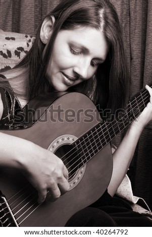 Beautiful mature brunette female playing the guitar