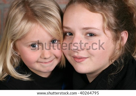 Two beautiful blond sisters holding one another close