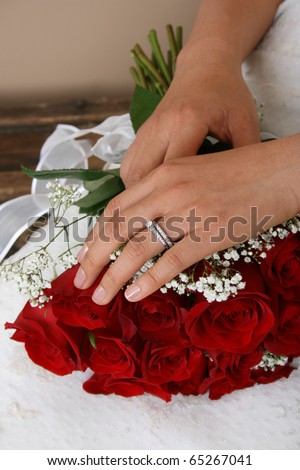Bride resting her hand on a red rose bridal bouquet