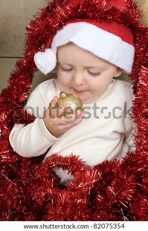 Cute baby boy wearing a christmas hat playing with decorations