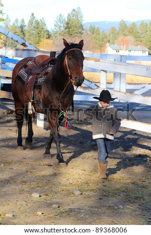 Young boy leading his horse in the riding pen