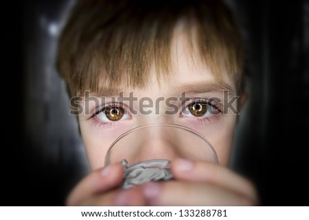 Hypnotic gaze of a young five year old boy drinking water