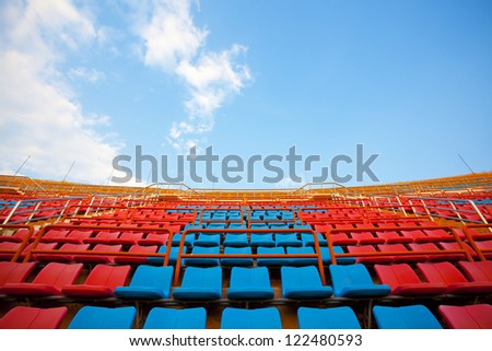 stadium seats, red  and blue seats on stadium steps bleacher up bright sky