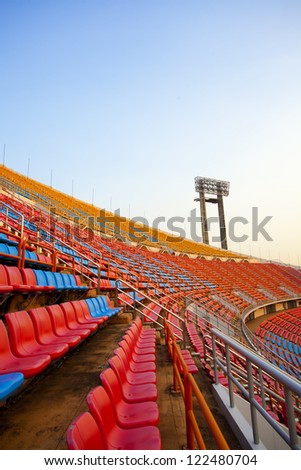 second floor, red and blue stadium seats curve rows on stadium with spot light pole