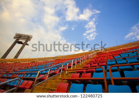 stadium, red  and blue seats on stadium steps bleacher with spot light pole up bright sky