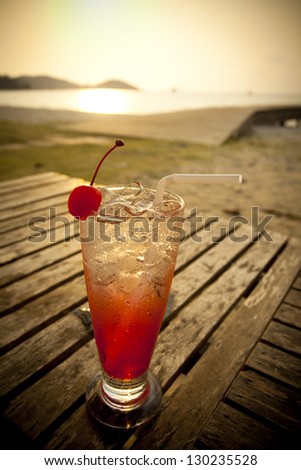red cocktail, red spirit drink in tall glass decorated cherry by the sea