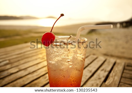 cherry cocktail by the sea, red spirit drink in tall glass decorated cherry by the sea