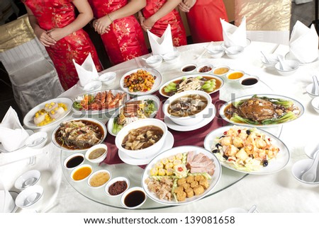 Chinese food, full rounded table of Chinese food with waitress behind