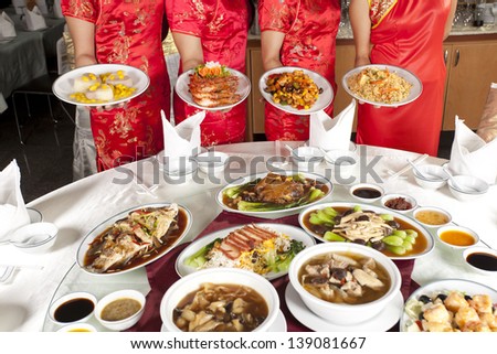 Chinese food, full rounded table of Chinese food with waitress behind